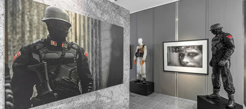 Pasillo de exposición con trajes tácticos y trajes de Terminator entre paneles.